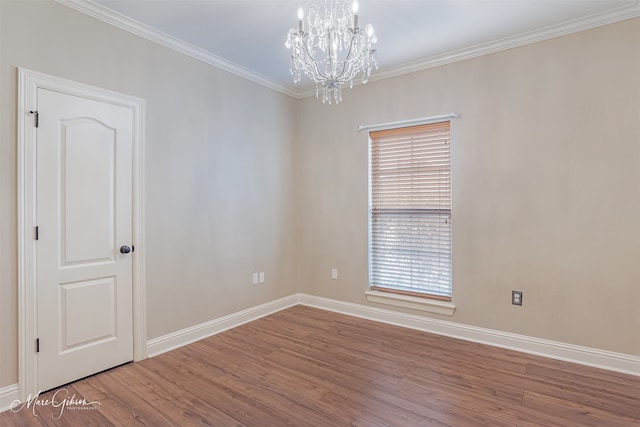 spare room with hardwood / wood-style flooring, crown molding, and a chandelier