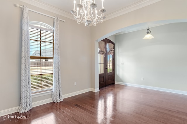 empty room with crown molding, a notable chandelier, dark hardwood / wood-style floors, and a wealth of natural light