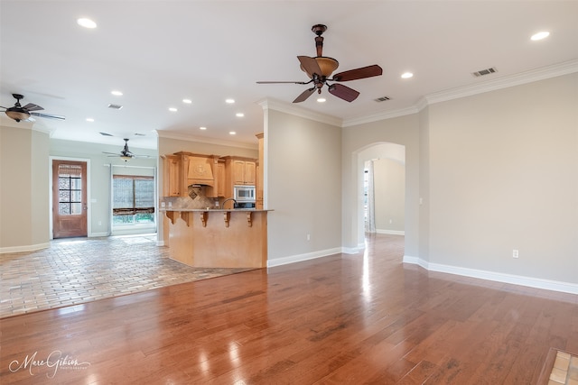 unfurnished living room featuring crown molding, hardwood / wood-style floors, and ceiling fan