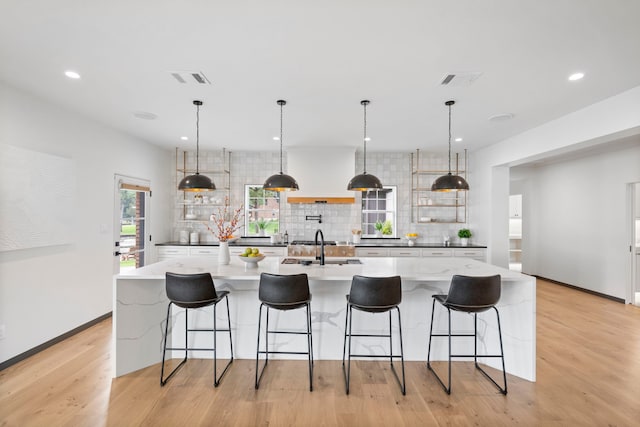 kitchen featuring a large island with sink, hanging light fixtures, a kitchen breakfast bar, and decorative backsplash