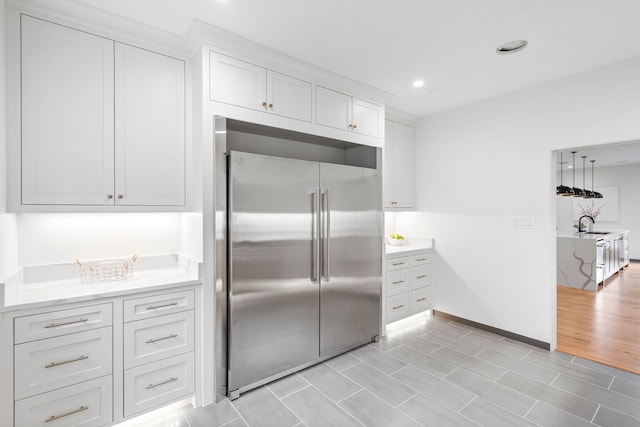 kitchen featuring white cabinetry, high end fridge, and sink