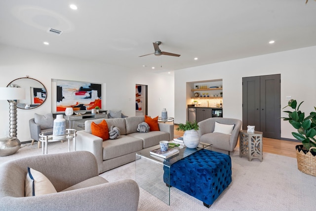 living room with light hardwood / wood-style flooring, ceiling fan, and indoor bar