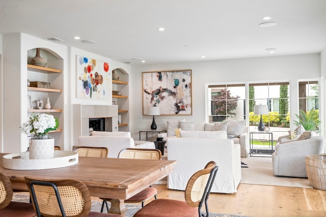 dining area with built in features, a fireplace, and light hardwood / wood-style floors