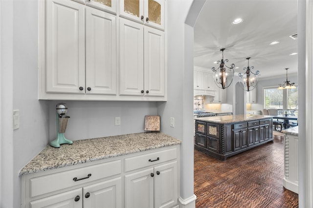 909 Reflection Ct, Heath, TX 75032 - kitchen with arched walkways, white cabinetry, a chandelier, recessed lighting, and light stone counters