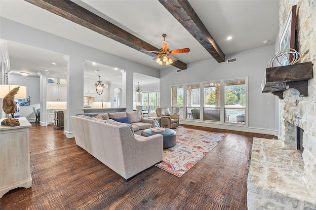 living room with beam ceiling, a stone fireplace, ceiling fan with notable chandelier, and dark hardwood / wood-style flooring