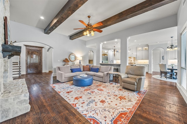 living room with beamed ceiling, dark hardwood / wood-style flooring, and ceiling fan with notable chandelier