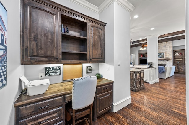 home office featuring decorative columns, dark wood-type flooring, built in desk, and ceiling fan