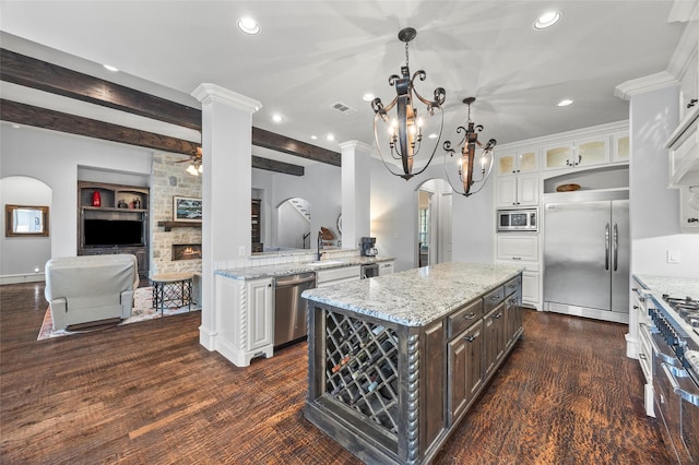 kitchen with dark brown cabinetry, built in appliances, a kitchen island, and white cabinets