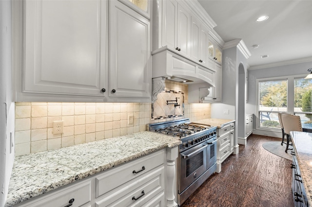 kitchen with dark wood-type flooring, crown molding, light stone countertops, range with two ovens, and white cabinets