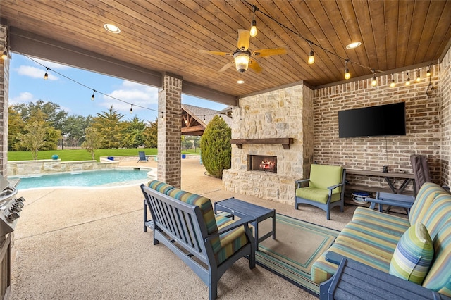 view of patio with ceiling fan and an outdoor living space with a fireplace