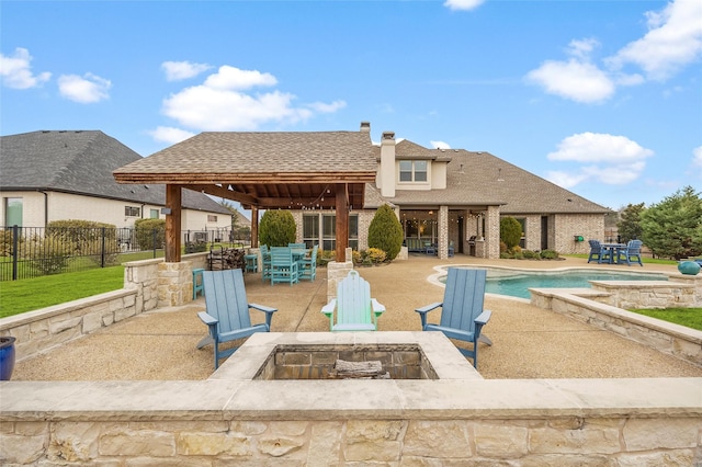 back of property featuring a swimming pool with hot tub, a fire pit, and a patio