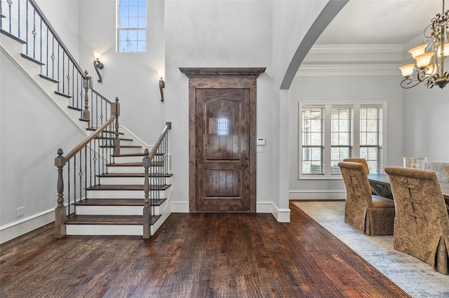 entrance foyer with an inviting chandelier, a healthy amount of sunlight, dark hardwood / wood-style floors, and crown molding