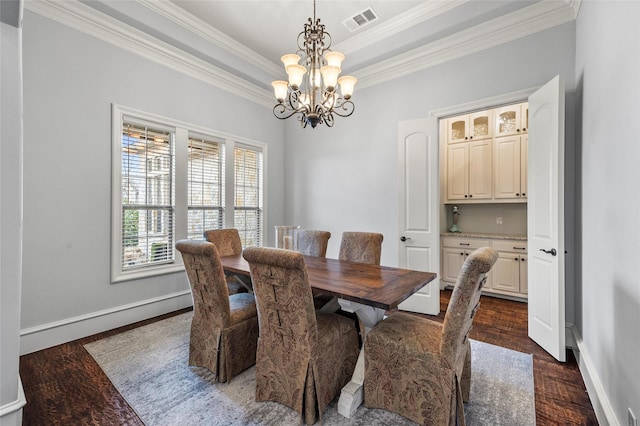 dining space featuring a tray ceiling, dark wood-type flooring, ornamental molding, and a chandelier