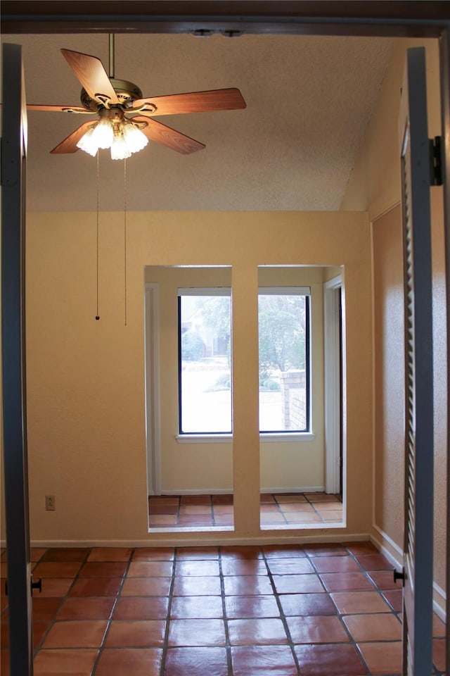 interior space with vaulted ceiling, tile patterned floors, and ceiling fan