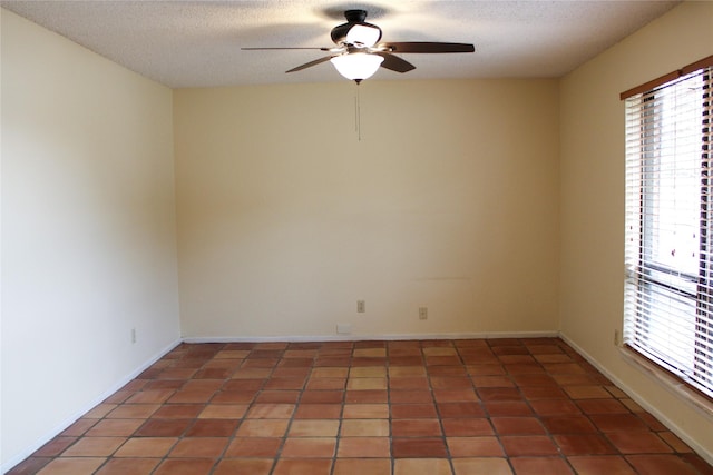 spare room featuring dark tile patterned floors, ceiling fan, a healthy amount of sunlight, and a textured ceiling