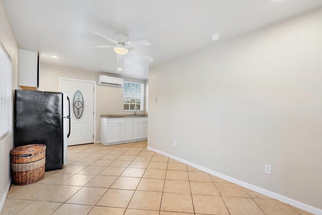 kitchen with light tile patterned floors, stainless steel fridge, ceiling fan, white cabinetry, and a wall mounted AC