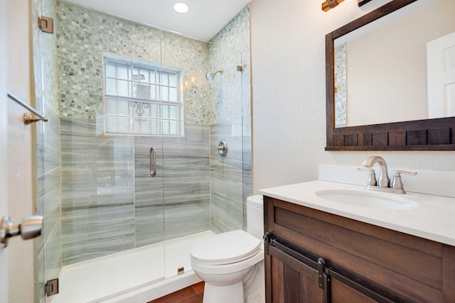 bathroom with a shower with door, vanity, and toilet