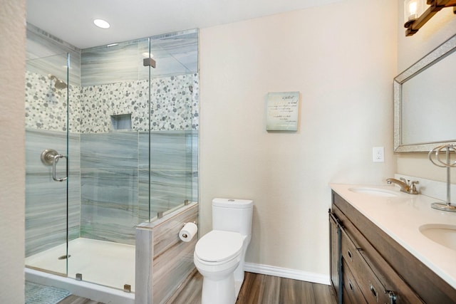 bathroom featuring vanity, toilet, a shower with door, and wood-type flooring