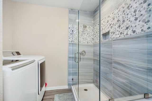 bathroom featuring an enclosed shower, hardwood / wood-style floors, and washer and dryer