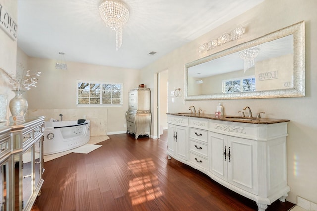 bathroom featuring vanity, a bathtub, wood-type flooring, and an inviting chandelier