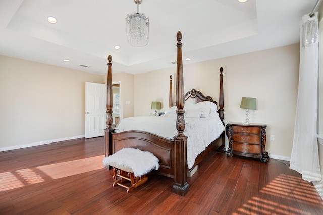 bedroom featuring a raised ceiling and dark hardwood / wood-style flooring