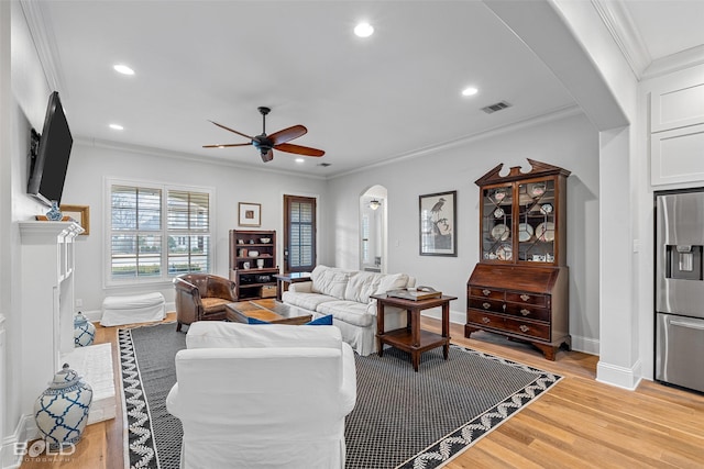 living room with ornamental molding, ceiling fan, and light wood-type flooring