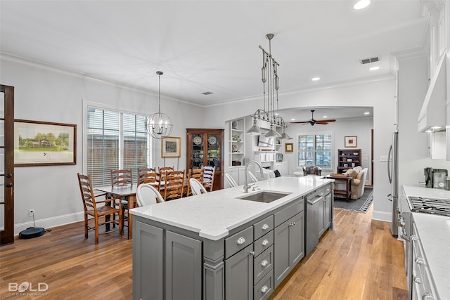 kitchen with sink, gray cabinetry, pendant lighting, stainless steel appliances, and a kitchen island with sink