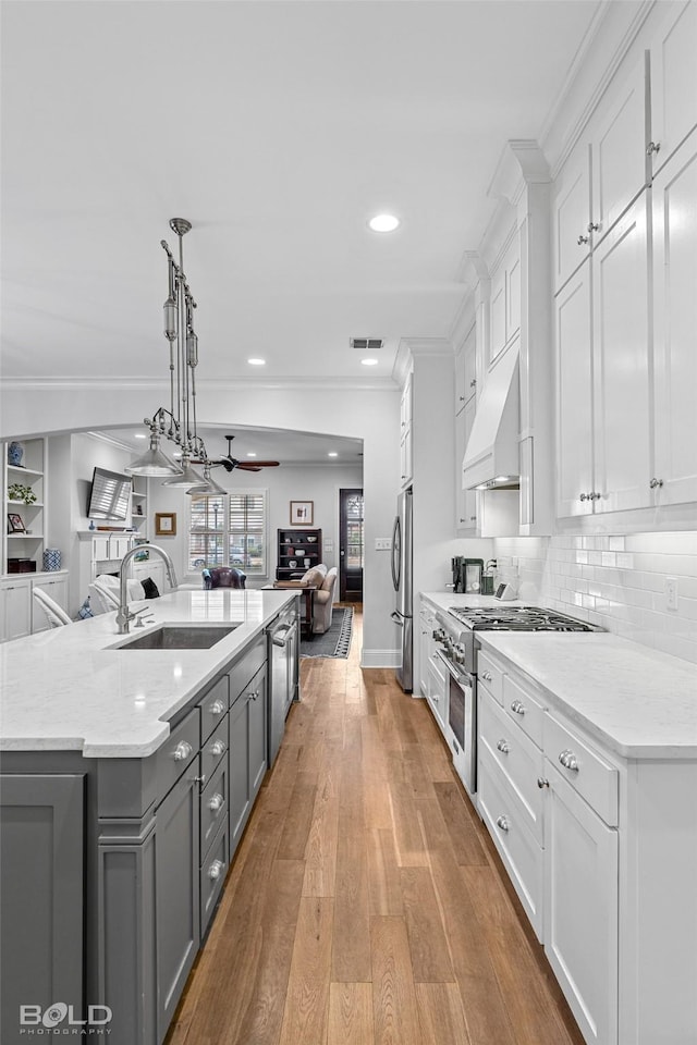 kitchen with white cabinetry, sink, custom exhaust hood, and pendant lighting