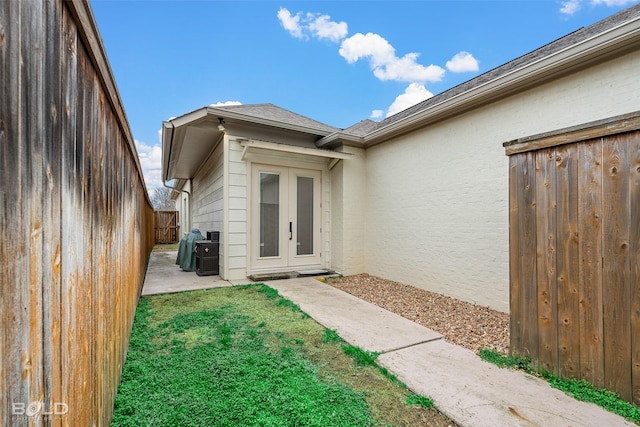 entrance to property featuring french doors, a patio area, and a lawn