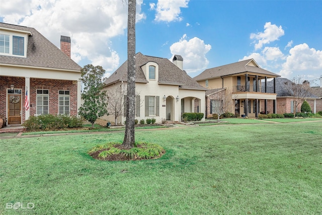 view of front of house with a front yard and a balcony