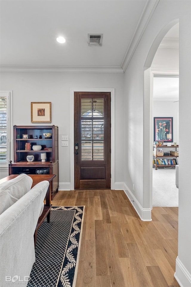 foyer featuring hardwood / wood-style flooring, crown molding, and a healthy amount of sunlight