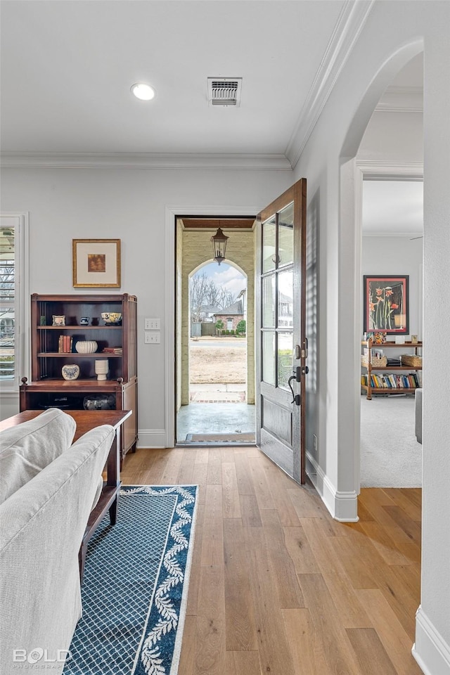 entryway with crown molding and light hardwood / wood-style floors