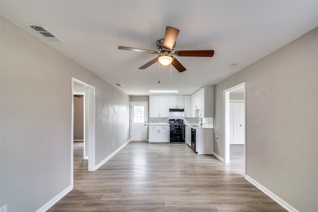 kitchen featuring a sink, visible vents, light countertops, range hood, and black gas range oven