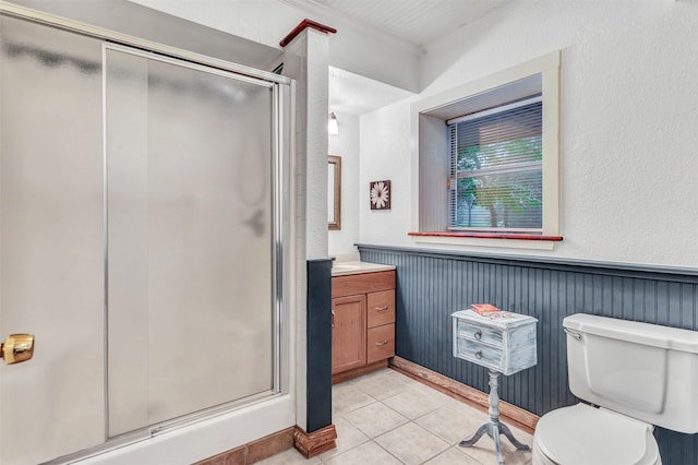 bathroom featuring tile patterned floors, toilet, a shower with door, and vanity