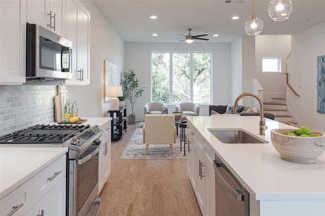 kitchen with stainless steel appliances, hanging light fixtures, and white cabinets