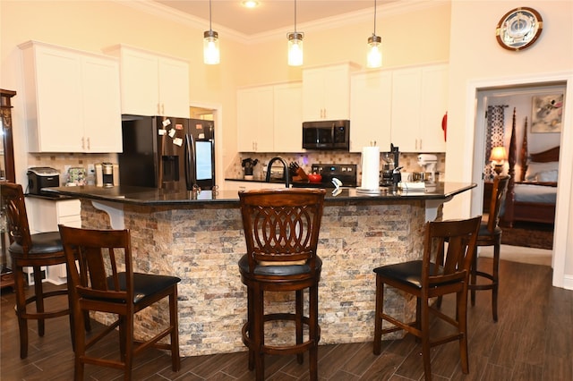 kitchen featuring a kitchen bar, black fridge, range with electric stovetop, decorative backsplash, and white cabinets