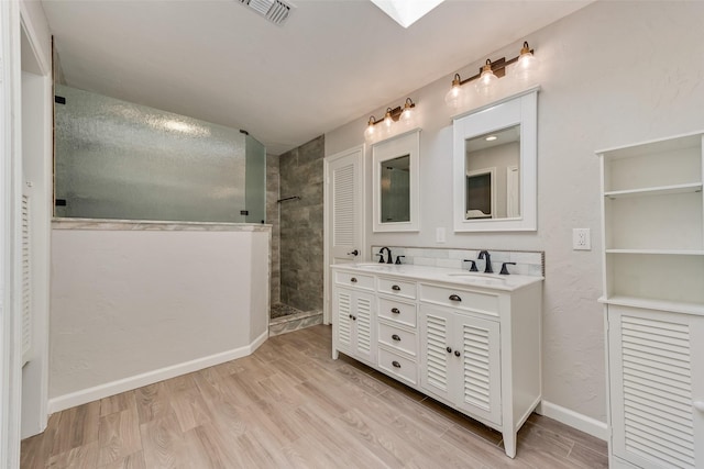 bathroom with hardwood / wood-style flooring, vanity, and tiled shower