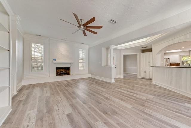 unfurnished living room featuring crown molding, ceiling fan, a fireplace, and light hardwood / wood-style flooring