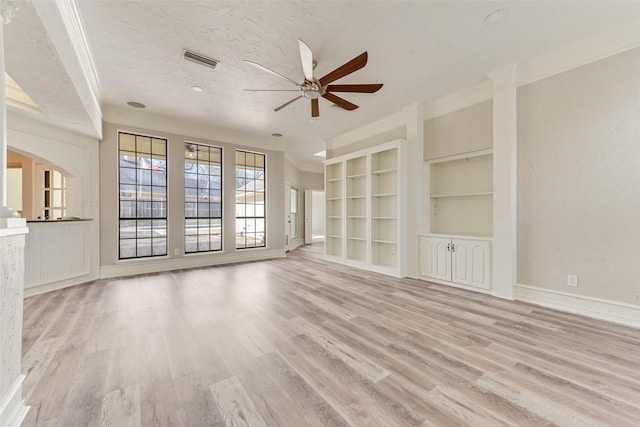 unfurnished living room with built in shelves, light hardwood / wood-style flooring, a textured ceiling, ornamental molding, and ceiling fan