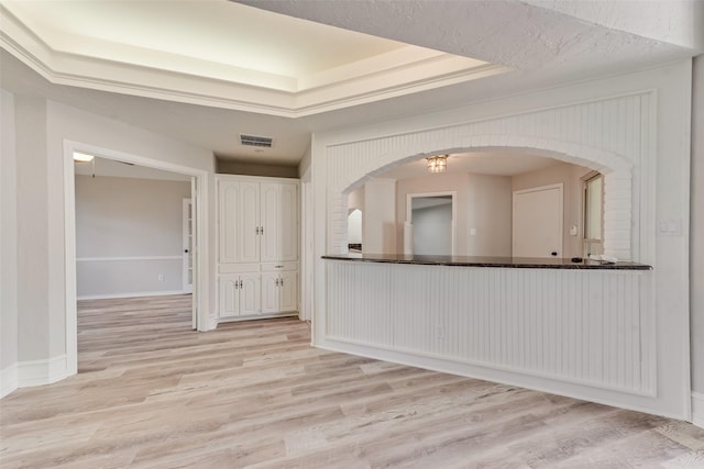 unfurnished room featuring a tray ceiling and light hardwood / wood-style flooring