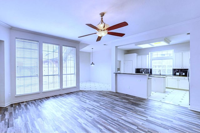 kitchen with crown molding, light wood-type flooring, sink, and white cabinets