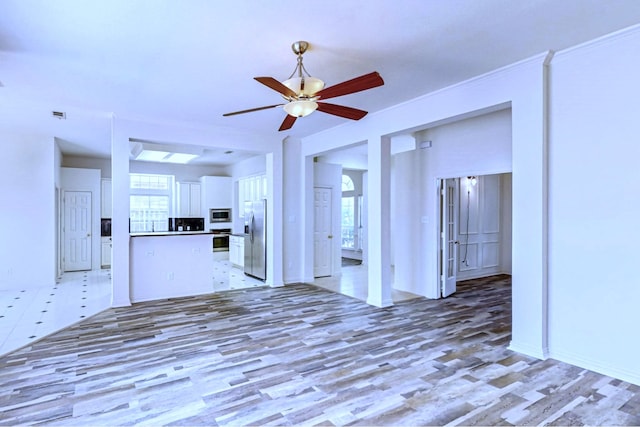 unfurnished living room featuring a healthy amount of sunlight, ceiling fan, and light hardwood / wood-style flooring