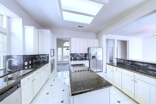 kitchen with a kitchen island, appliances with stainless steel finishes, sink, white cabinets, and dark stone counters