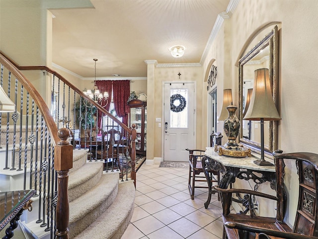 tiled foyer entrance with ornamental molding and a chandelier