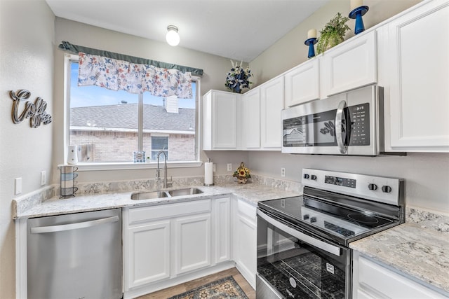 kitchen with white cabinetry, sink, stainless steel appliances, and light stone countertops