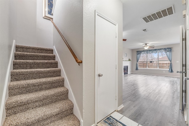 staircase with hardwood / wood-style floors and ceiling fan