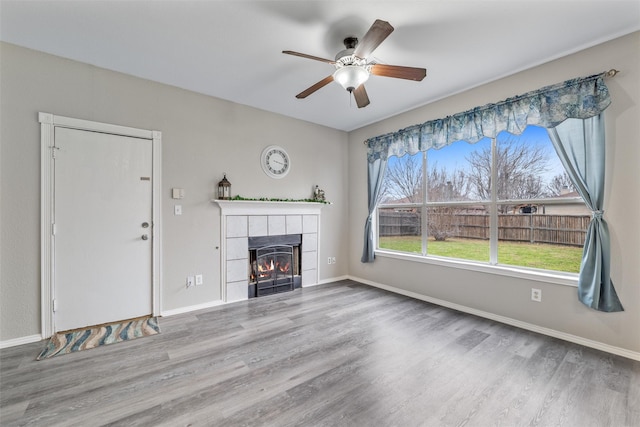 unfurnished living room with hardwood / wood-style flooring, a tile fireplace, and ceiling fan