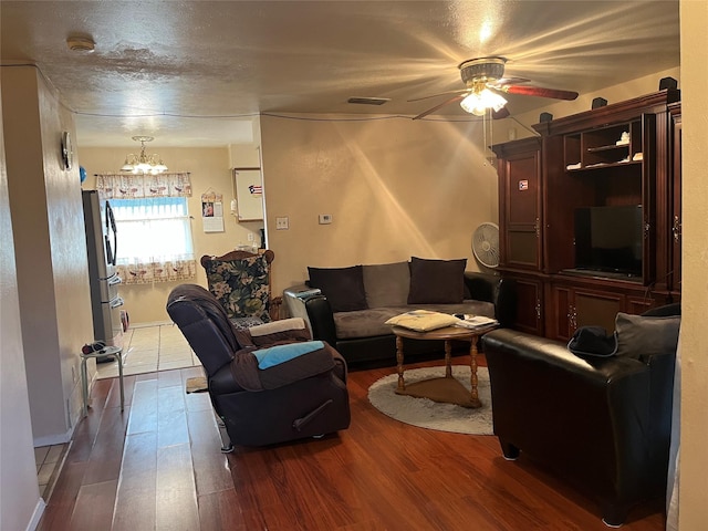 living room with hardwood / wood-style flooring and ceiling fan with notable chandelier