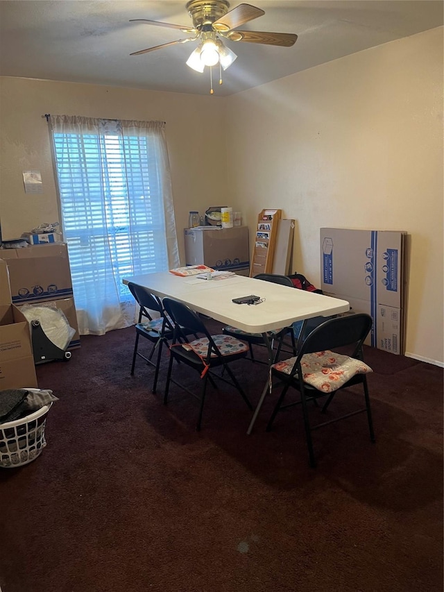 dining space with ceiling fan and dark carpet