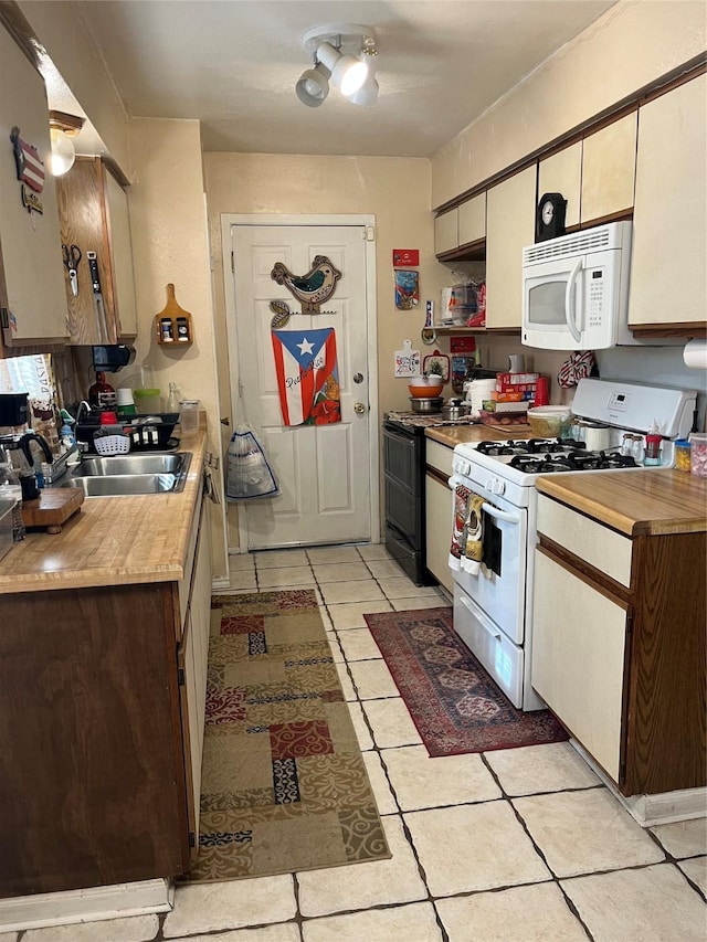 kitchen featuring light tile patterned flooring, sink, and white appliances